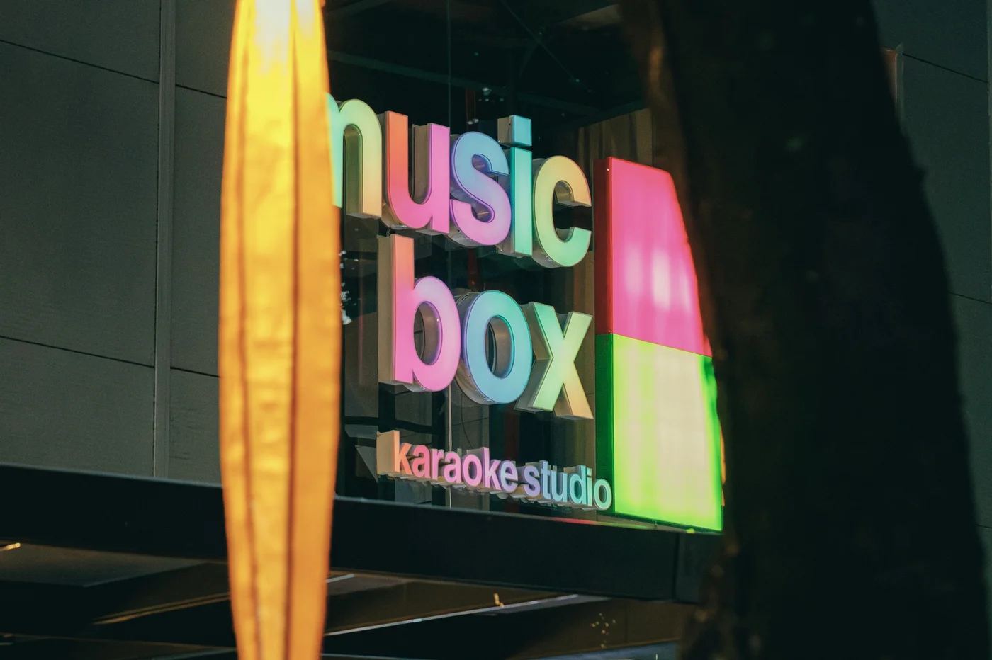 Fachada do Music Box Karaokê Studio com letreiro em neon colorido