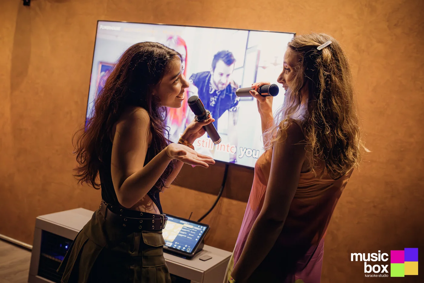 Duas amigas cantando karaokê em frente à tela